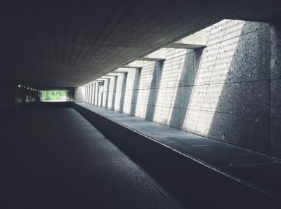 Architectural view of a concrete tunnel featuring striking sunlight pa — Photo by Anton Porsche on Pexels