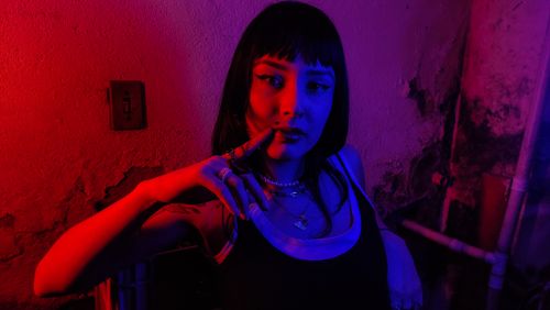Free Moody portrait of a fashionable woman indoors with red and blue lighting. Stock Photo