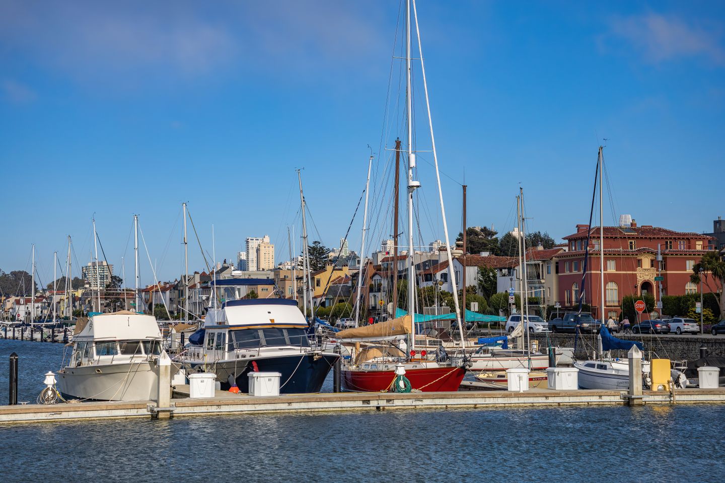 Sailboats moored at Marina del Rey waterfront with colorful buildings and clear blue sky