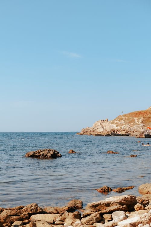 Free Beautiful coastal scene featuring rocky shorelines and clear blue sea under a bright sky. Stock Photo
