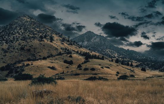 Explore the moody and dramatic landscape of rolling hills in this captivating countryside photo.