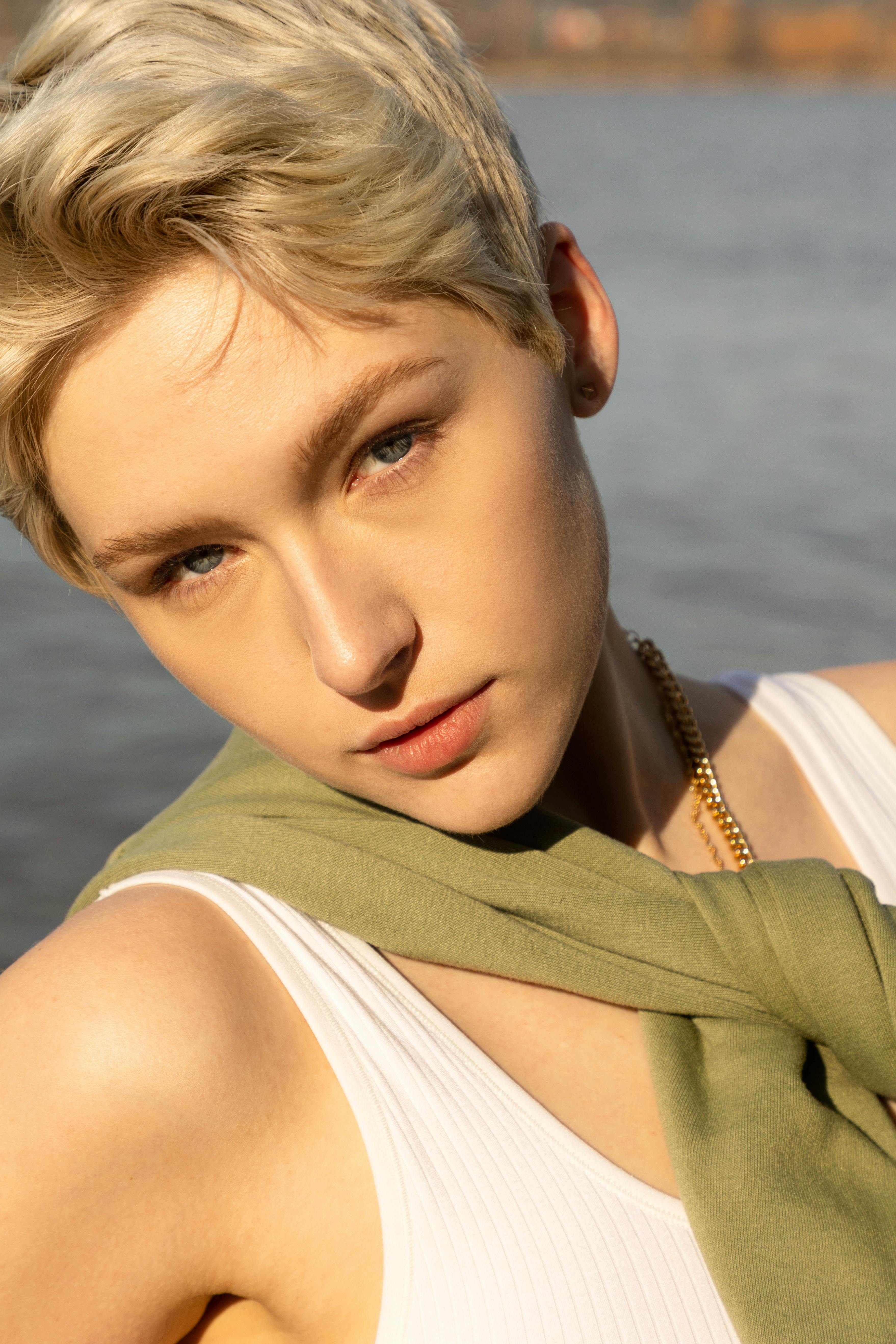 Portrait of a stylish blonde woman posing outdoors in natural light, showcasing elegance and modern fashion.