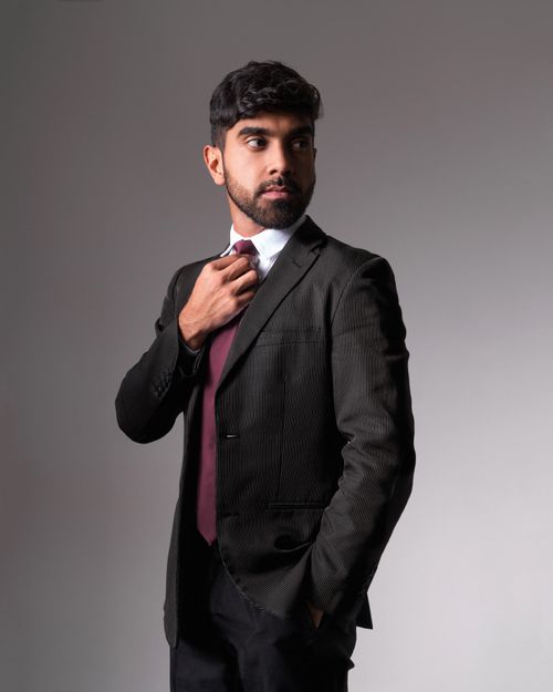 Free A professional man adjusting his tie, exuding confidence in a formal suit. Stock Photo