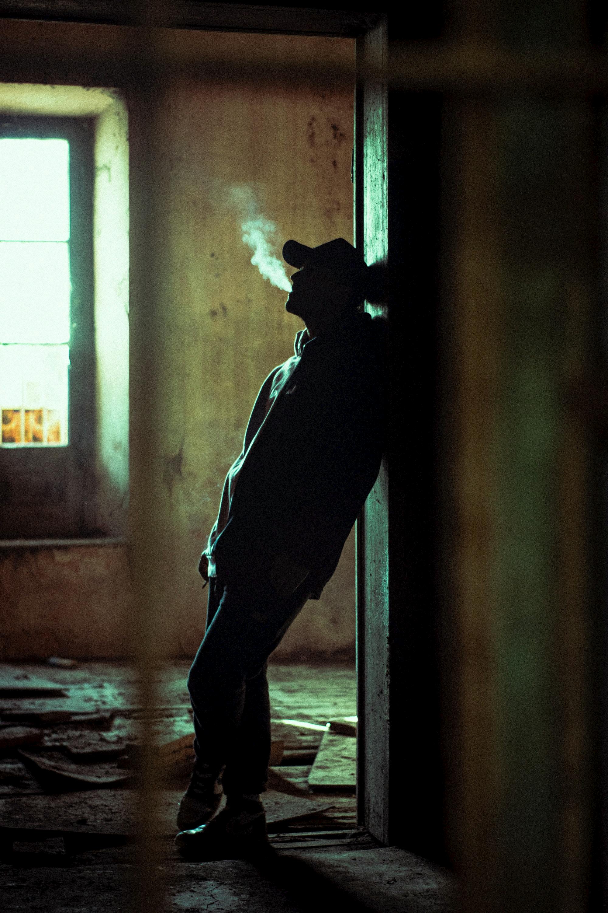 silhouette of man in abandoned house smoking