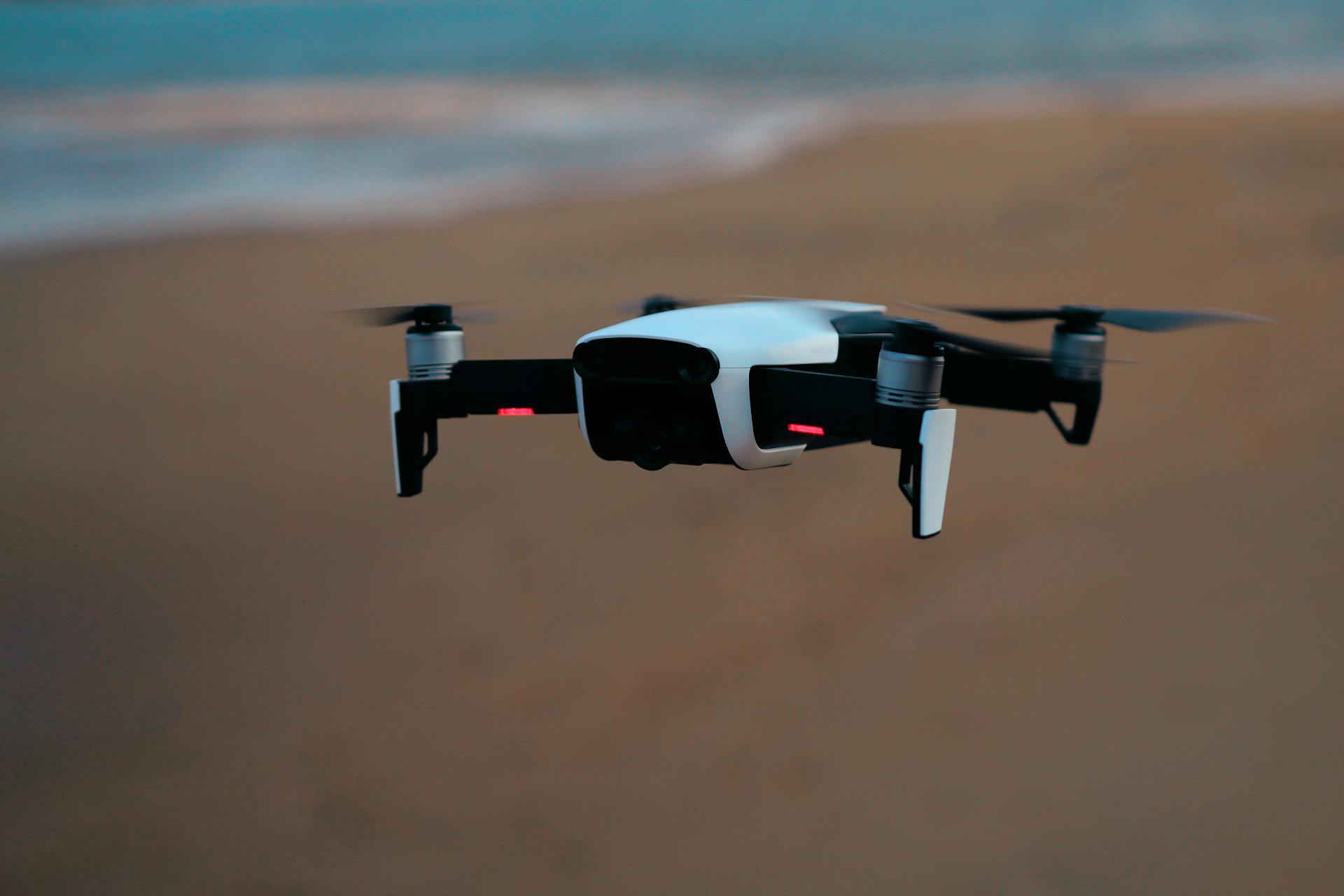 Aerial view of a modern drone flying over a sandy beach during sunset