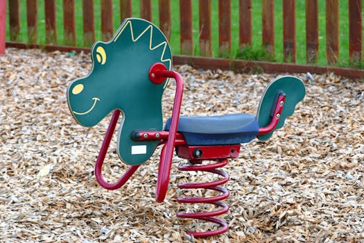 在铺有木片的户外操场上，一位色彩缤纷的恐龙主题骑手正进行春季骑行