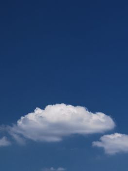 A single cumulus cloud floating in a clear blue sky, providing a peaceful and serene view.
