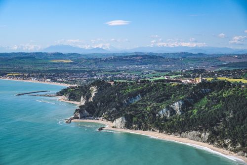 Free Stunning aerial shot of a coastline with lush greenery and a vibrant blue sea. Stock Photo