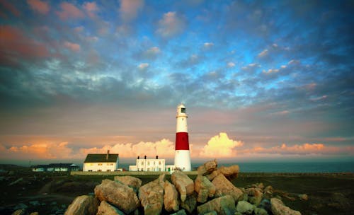 White and Red Lighthouse Near Rocks