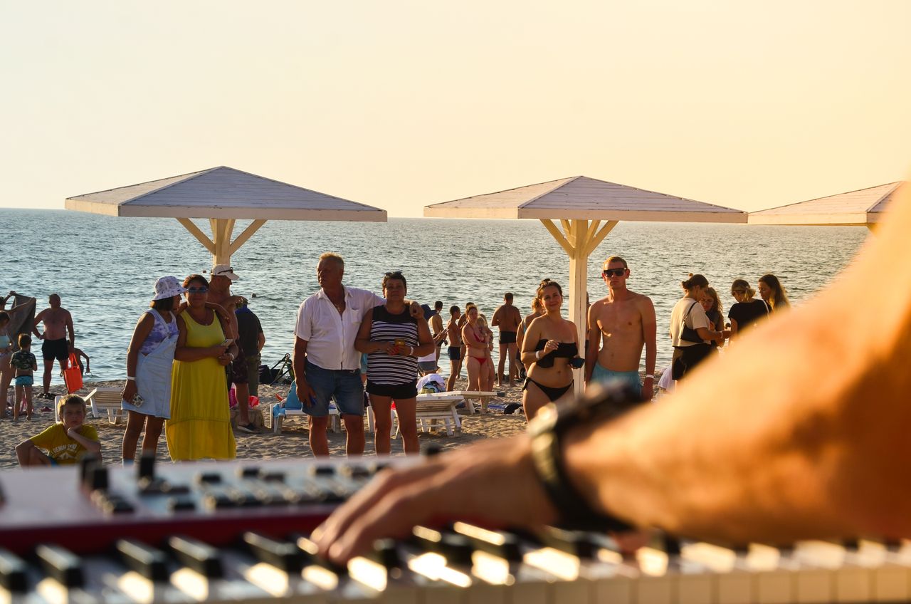 a lively beach scene with people enjoying a seaside concert under sun