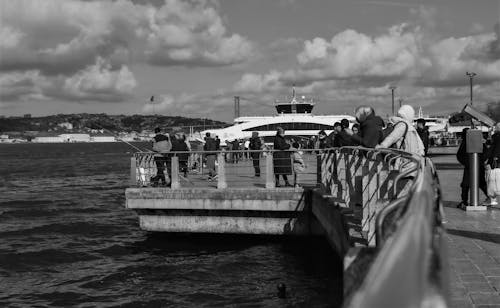 Grayscale Photo of People Walking on Concrete Dock