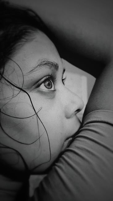 Close-up black and white portrait capturing the intense gaze of a young girl.