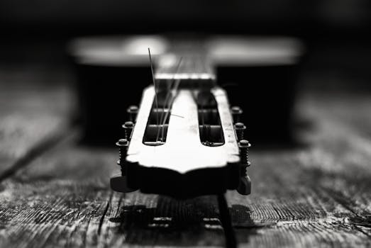Close-up of a guitar's headstock with strings, in black and white.