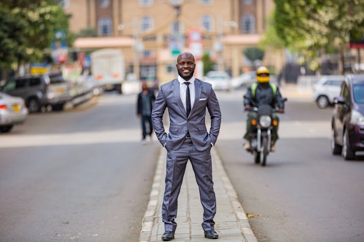 Man In Gray Suit Standing On Median Island On Street