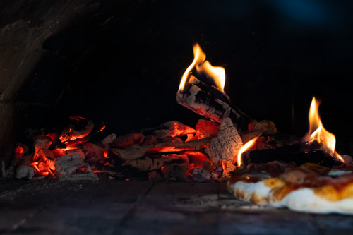 Free Close-up view of a wood-fired pizza oven with embers and a freshly baked pizza. Stock Photo