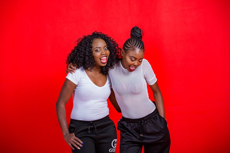 Smiling Women In Sportswear Posing On Red Studio Background