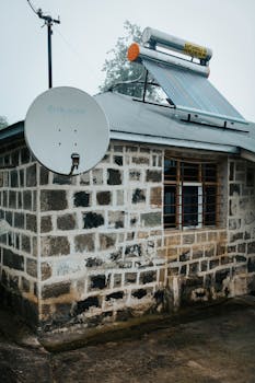 Stone exterior house with solar panel and satellite dish, showcasing sustainable energy solutions.
