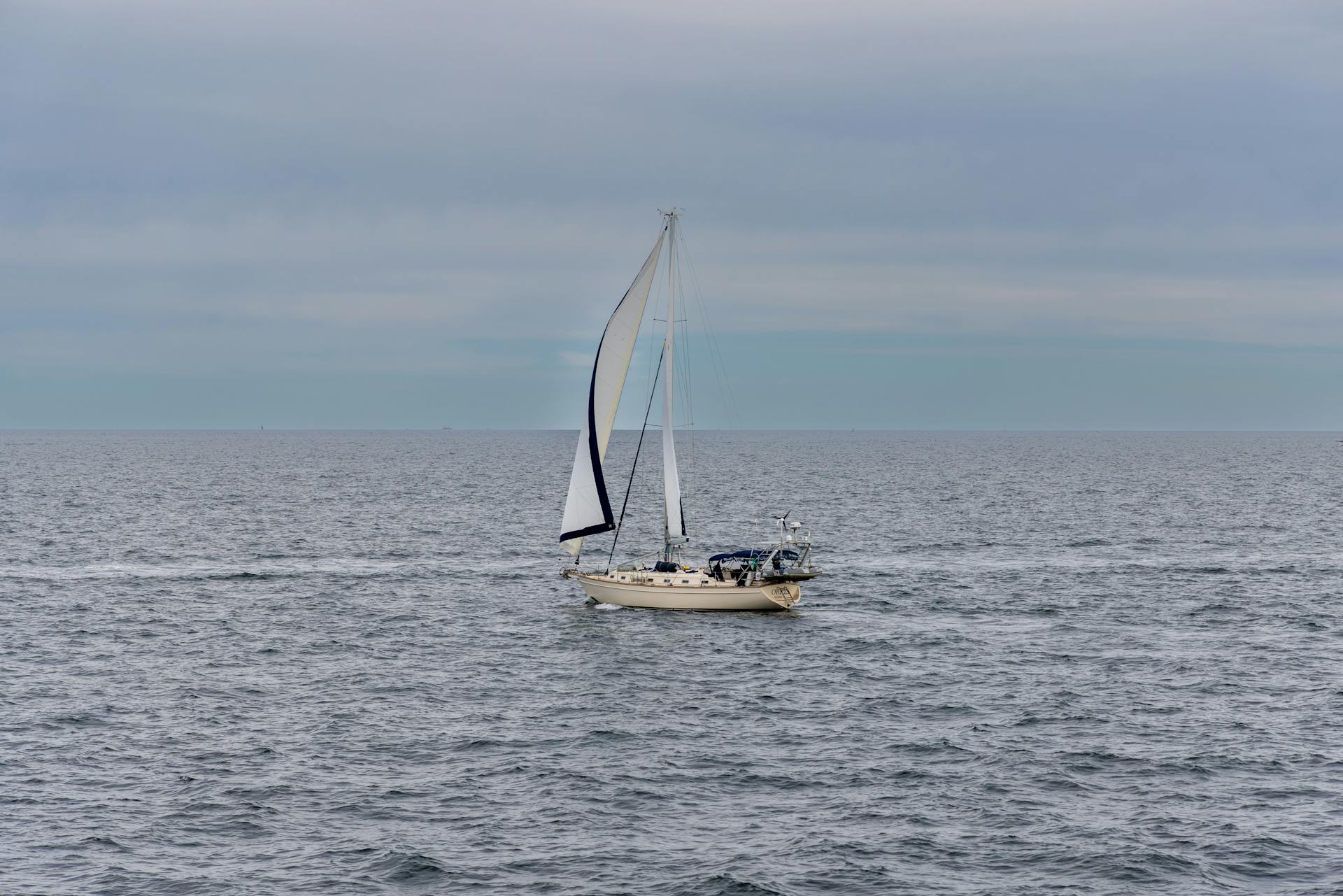 Sailing boat gliding on tranquil ocean waters near New Shoreham, RI amidst a serene sky.