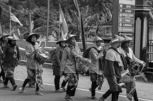 Grayscale Photo of Indonesian Women in Traditional Straw Hat Walking on Street