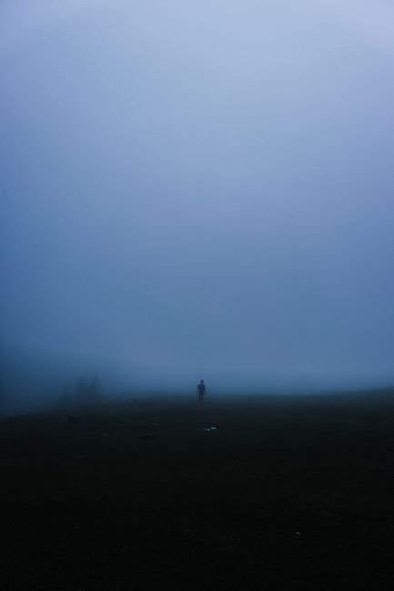 A mysterious silhouette stands in a dense foggy field in Kümbet, Giresun, Turkey, creating a moody atmosphere.