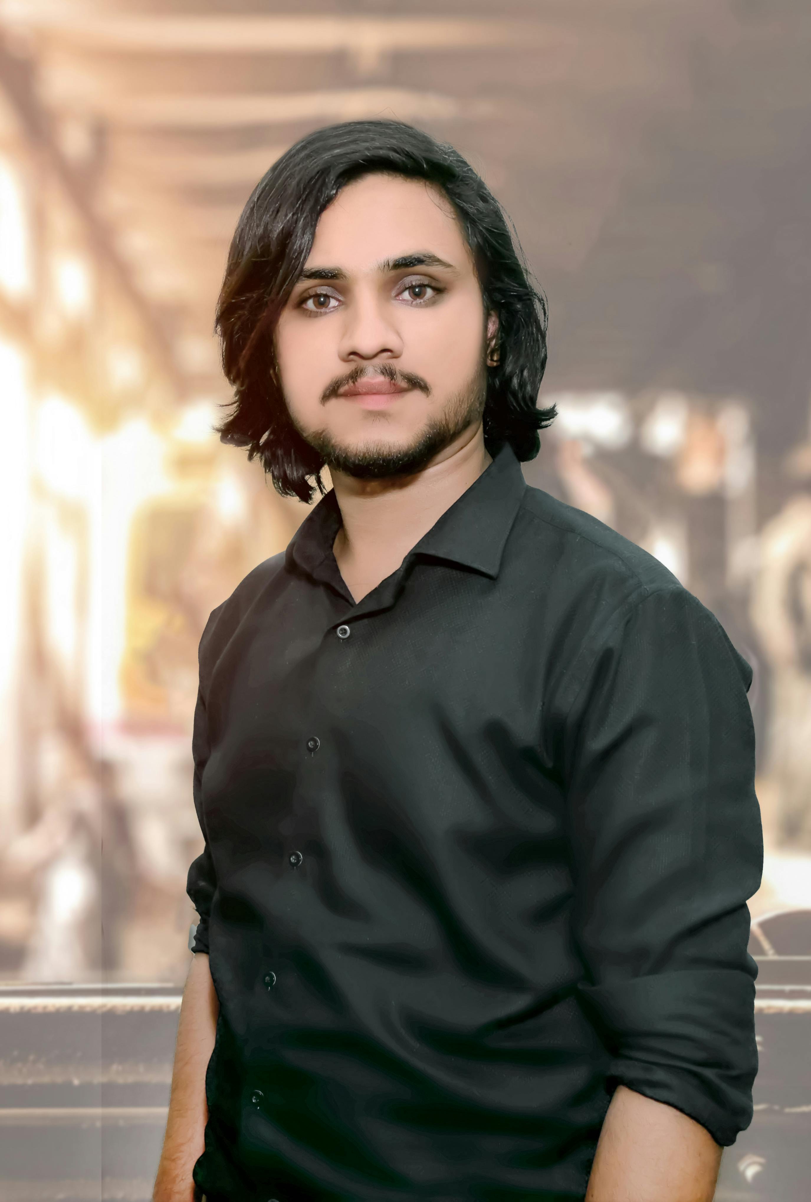 Stylish young man with black hair posing confidently indoors.