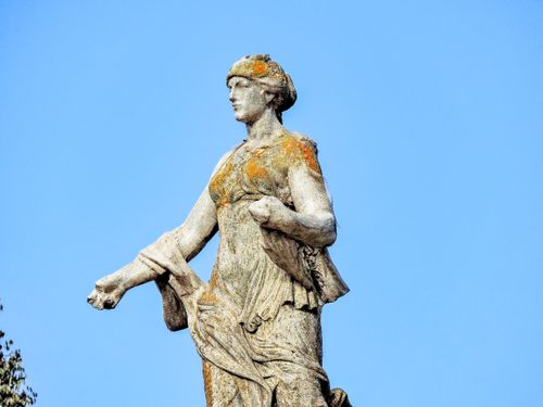 Free A detailed stone statue of a female figure with a clear blue sky background. Stock Photo