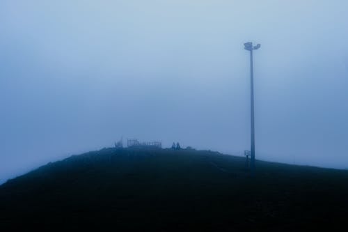 People Sitting on Hill in Fog