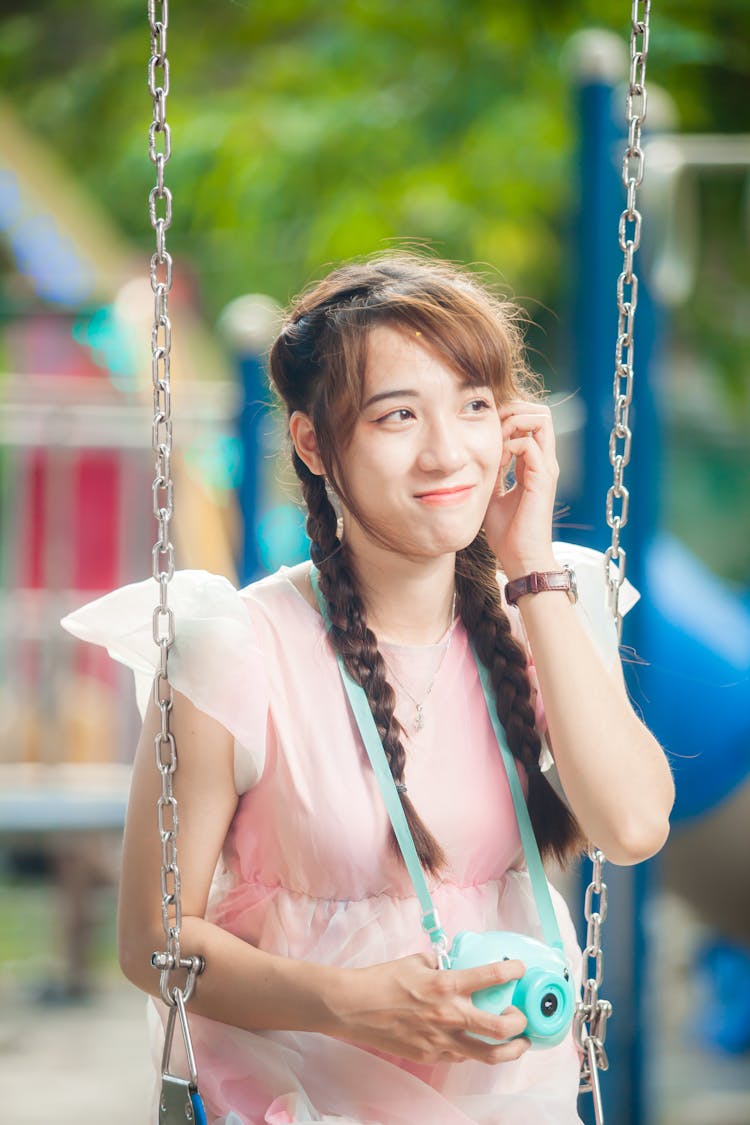 Woman With Braided Hair Sitting On A Swing