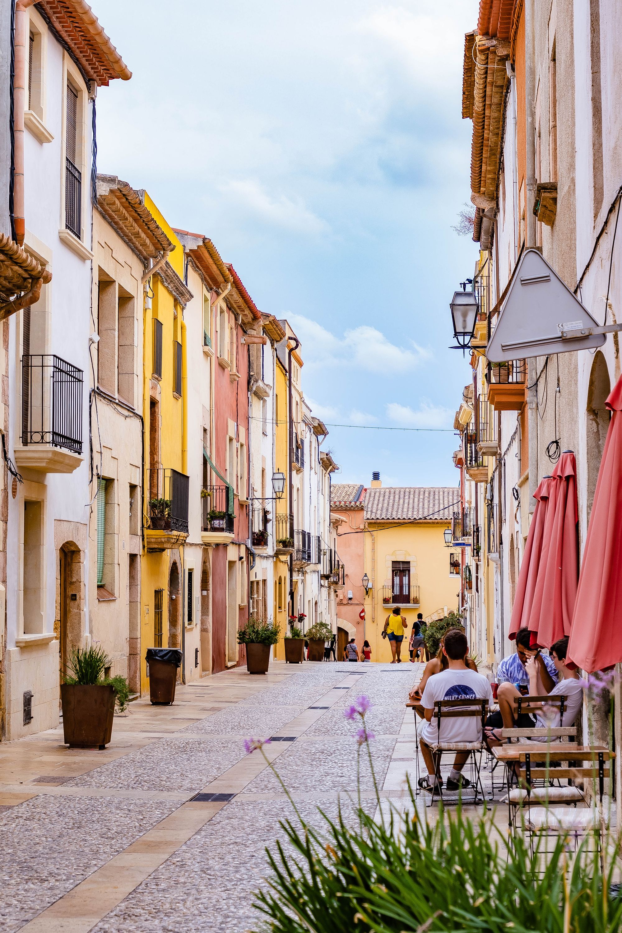 A colourful pedestrian street with café tables and people strolling in Altafulla, Catalunya.