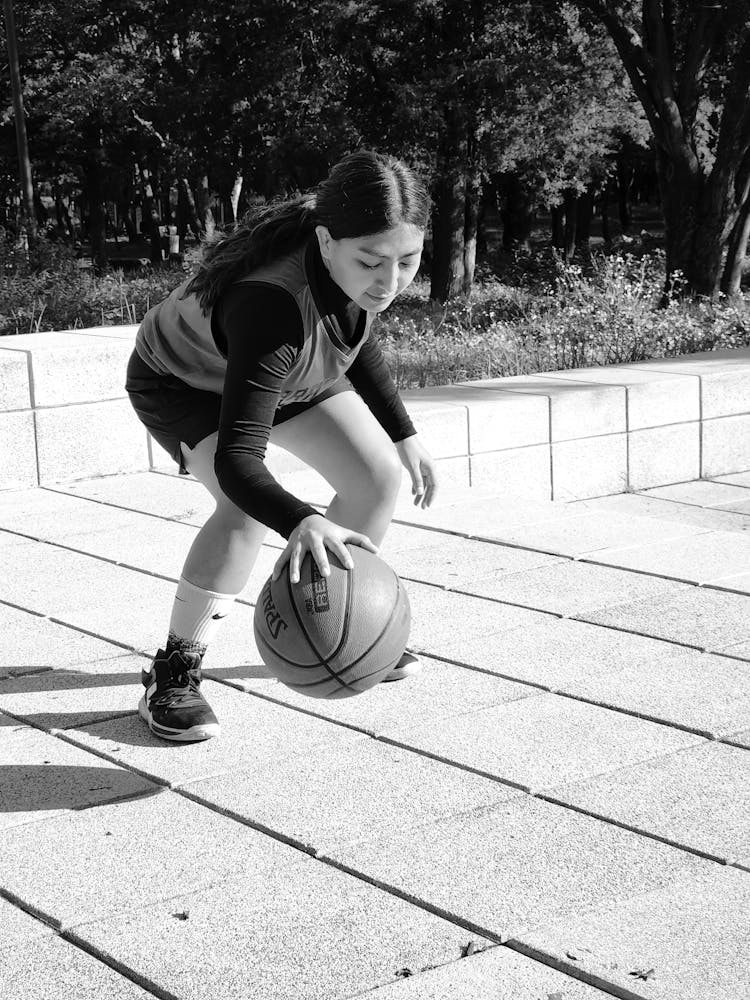 Grayscale Photo Of A Woman Dribbling A Ball