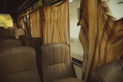 Interior view of a vintage bus with leather seats and striped curtains, evoking nostalgia.