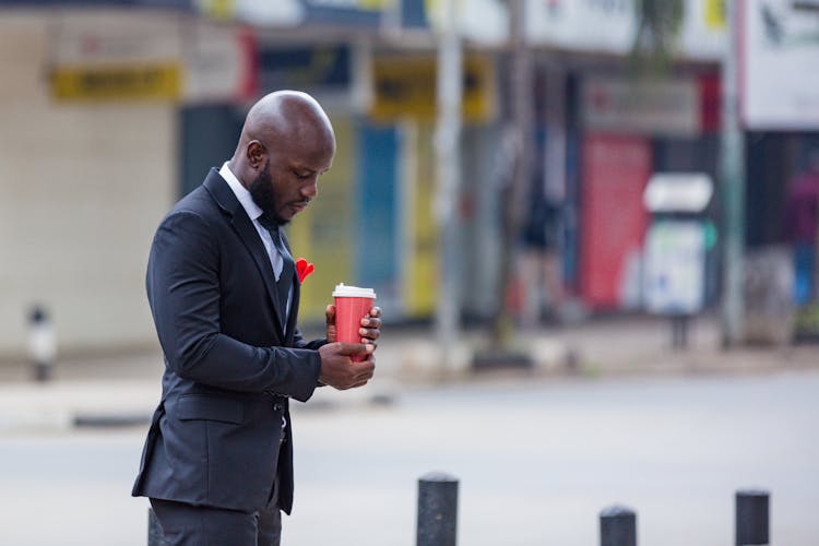 Man In A Suit With A Coffee Standing In The City Street 