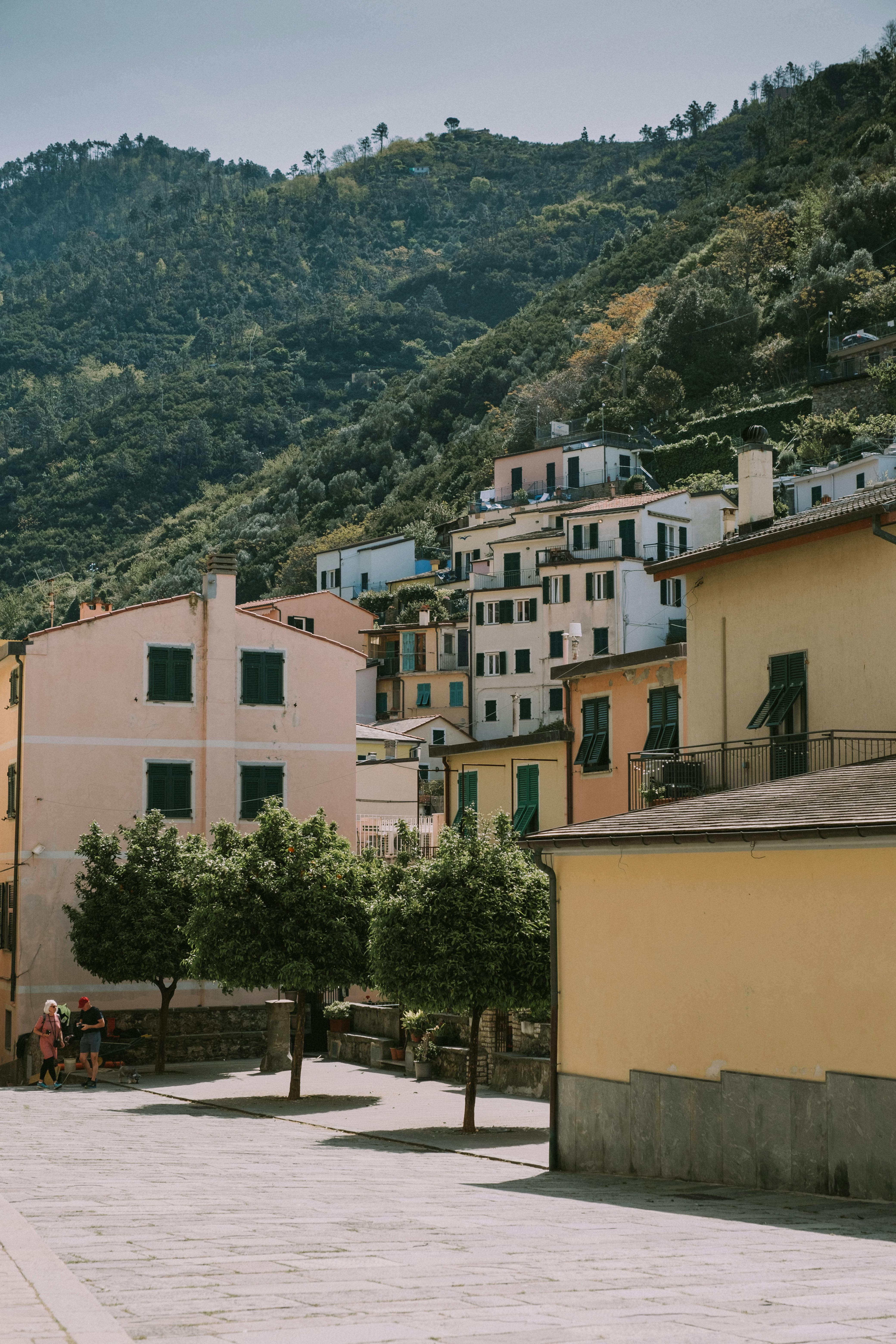 Explore the vibrant streets and colorful houses of Monterosso al Mare, Italy, nestled by lush mountains.