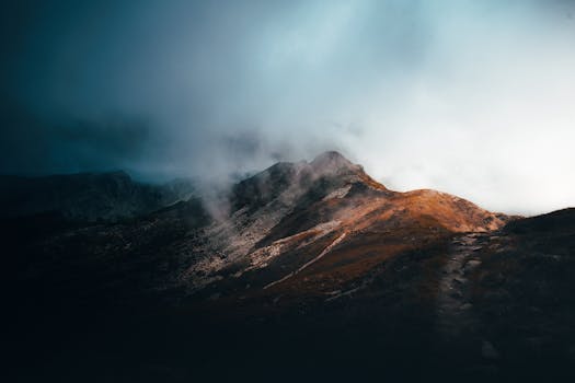 Fog envelops a rugged mountain in Veneto, Italy, creating a moody and dramatic scene.
