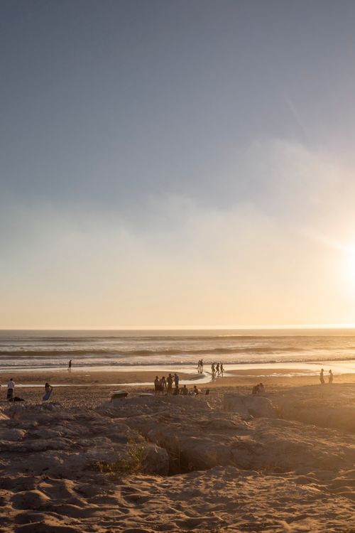 Free Serene beach at sunset with groups enjoying the ocean view. Stock Photo
