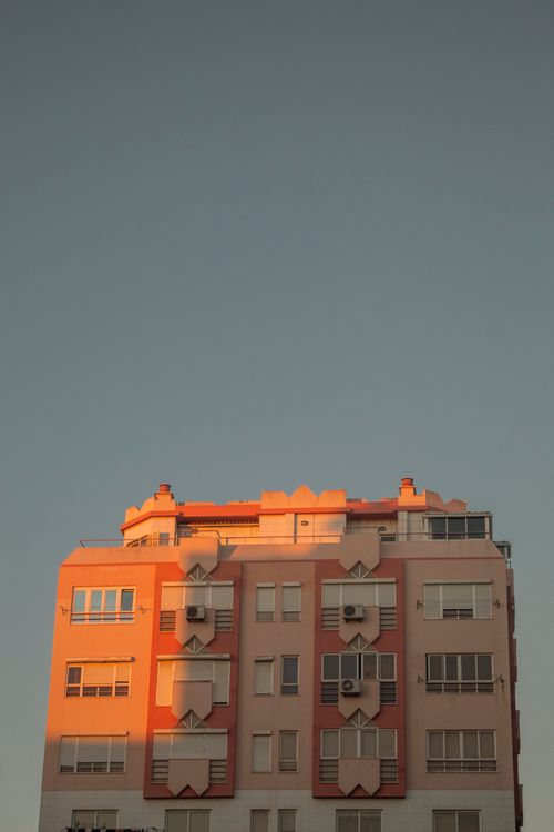 Free A modern residential building illuminated by sunset light under a clear sky. Stock Photo