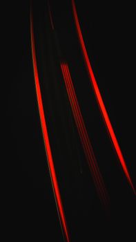 An artistic capture of dynamic red light trails against a dark background.
