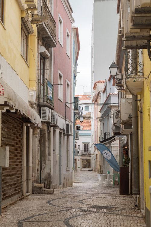 Free Explore a quaint narrow street with cobblestone paving and vibrant buildings, perfect for travel lovers. Stock Photo