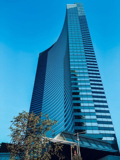 Free A stunning modern skyscraper featuring a sleek blue glass facade against a clear blue sky. Stock Photo