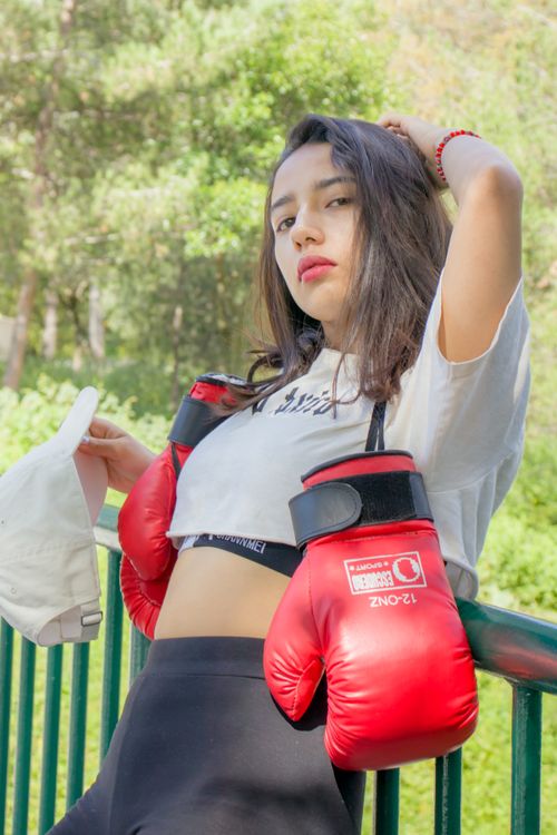 Free Confident woman standing with boxing gloves in an outdoor setting. Stock Photo