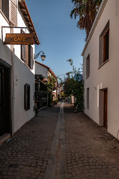 Free Quiet cobblestone alleyway with traditional facades and a quaint cafe sign. Stock Photo