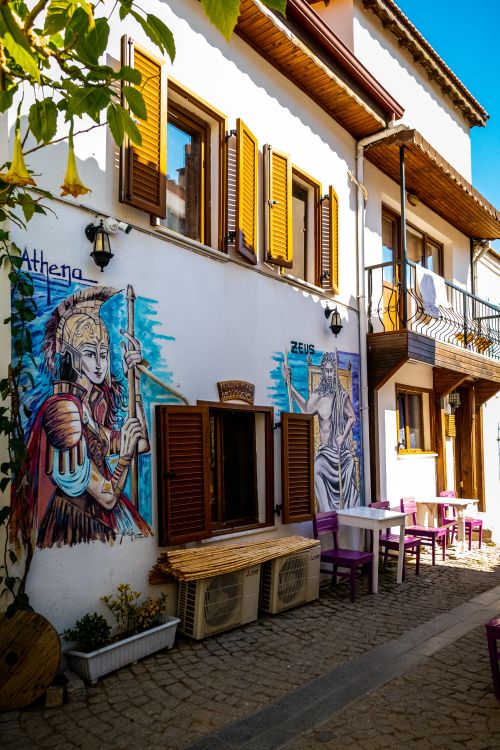 Free A vibrant Greek street scene featuring murals of Athena and Zeus on a sunlit facade. Stock Photo