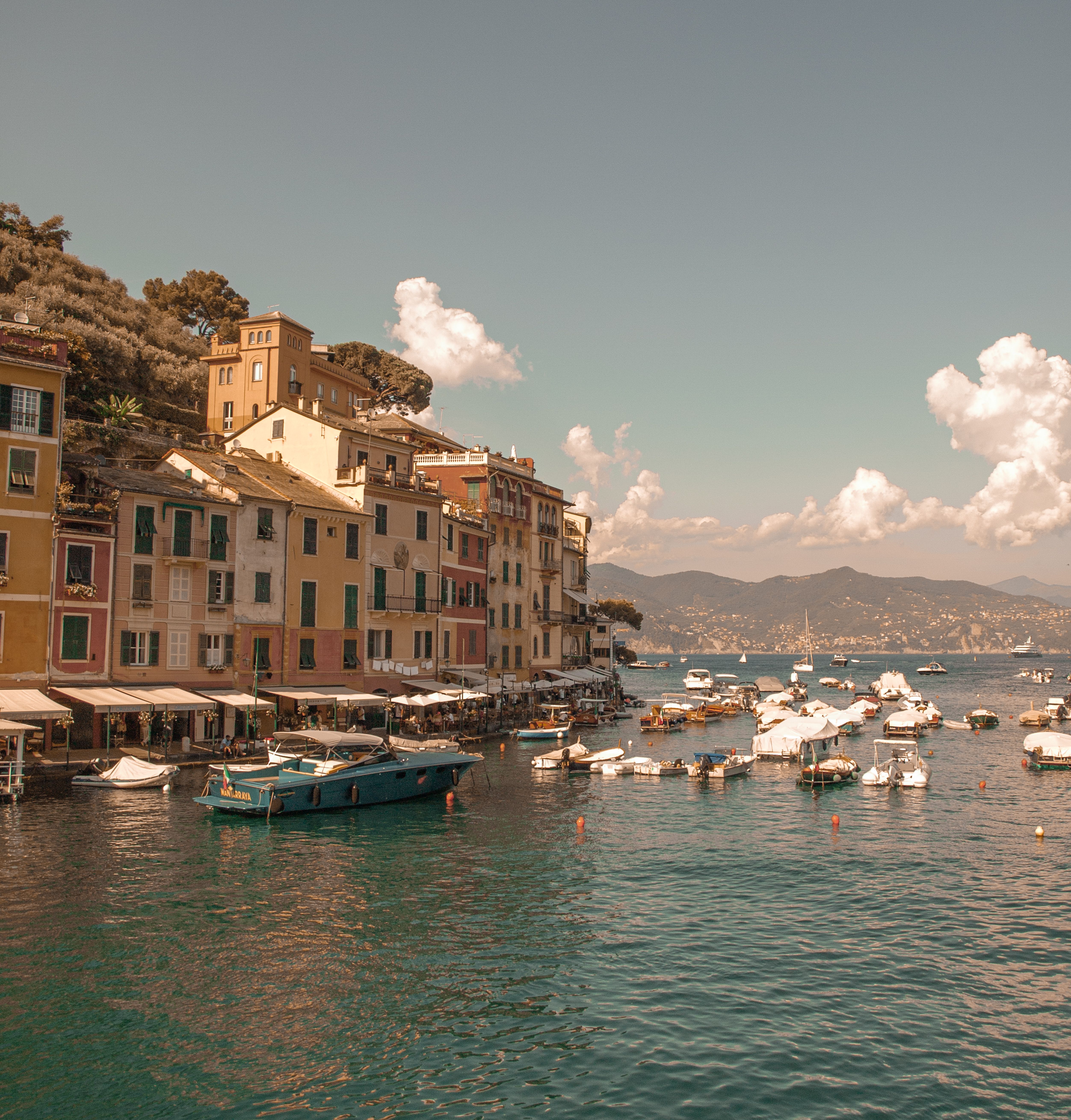 Charming view of Portofino harbor with colorful buildings and boats under a bright sky.