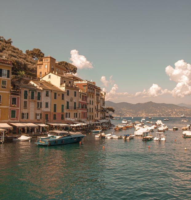 Charming view of Portofino harbor with colorful buildings and boats under a bright sky.