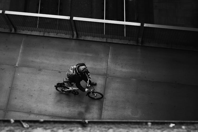 Grayscale Photo Of Person Pushing His Bike