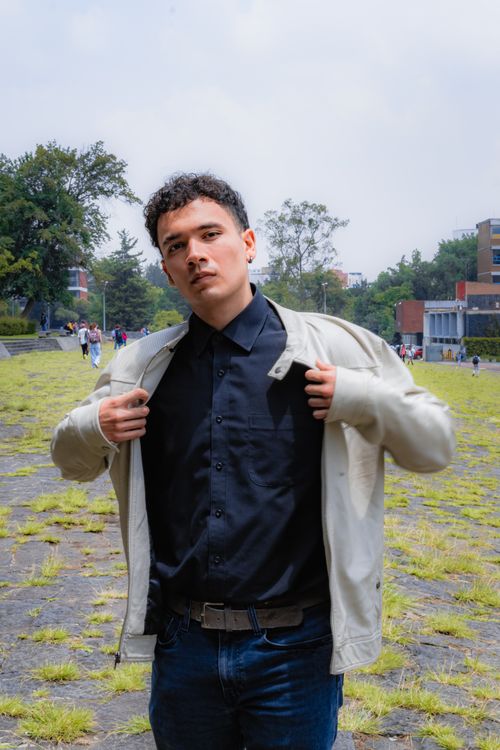 Free Portrait of a young man in a casual jacket posing confidently outdoors in a park. Stock Photo