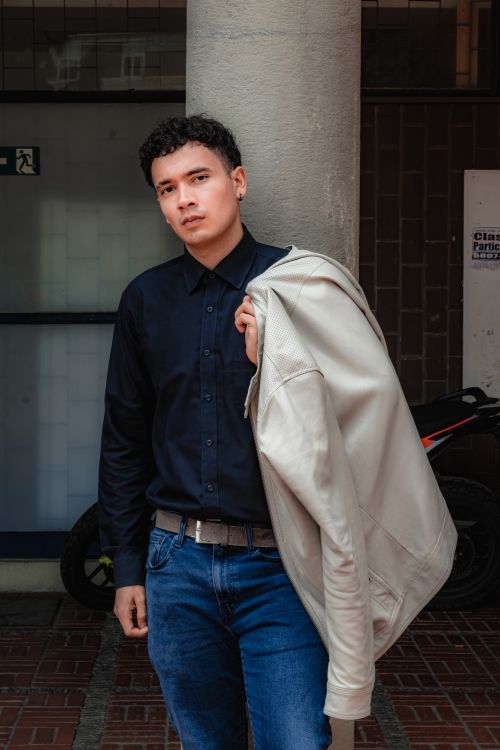 Free Young man in casual stylish outfit posing with jacket outdoors. Stock Photo