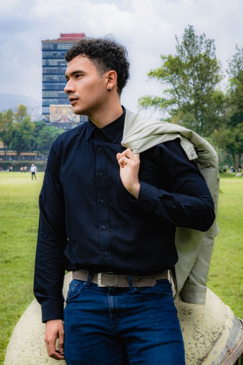 Free Fashionable young man in urban park with jacket over shoulder, stylish look. Stock Photo