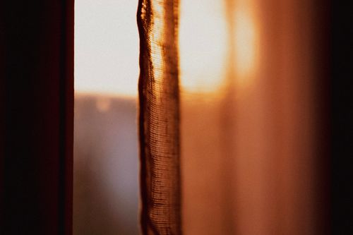 Free Sunlight streams softly through a sheer curtain, creating a warm, tranquil atmosphere. Stock Photo