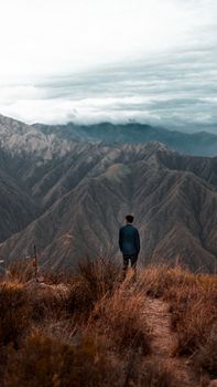 Man standing on a mountain peak in La Rioja, Argentina, gazing across scenic landscape